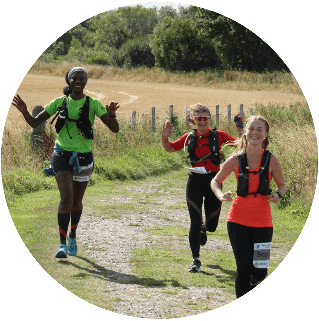 Three women raising there hands in a running event in the countryside